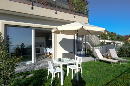 a table and chairs with an umbrella in a yard at Oasi Giardino - Pool and Lake View and Garden in Cissano
