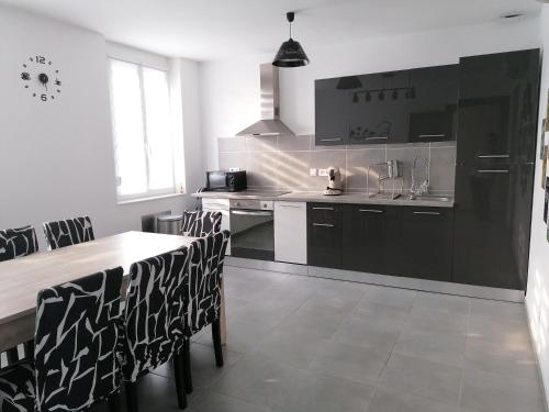 une cuisine avec des armoires noires, une table et des chaises dans l'établissement GAYANTINE - Spacieuse Confortable Proche Gayant Expo FIBRE, à Roost-Warendin