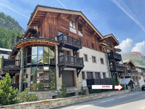 une maison en bois avec balcon sur le côté d'une rue dans l'établissement Magnifique appartement avec jacuzzi extérieur privé à Val d'Isère - FR-1-567-99, à Val dʼIsère