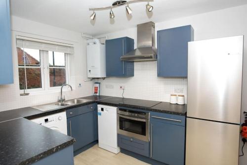 a kitchen with blue cabinets and a white refrigerator at Castle in Old Sarum