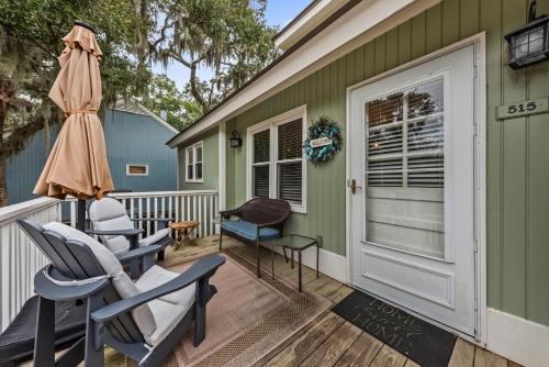 a front porch with chairs and an umbrella at 515 Tarpon Pond Cottage in Seabrook Island