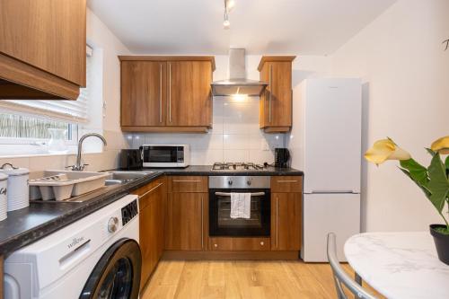 a kitchen with wooden cabinets and a white refrigerator at Terri's House in Newton-le-Willows