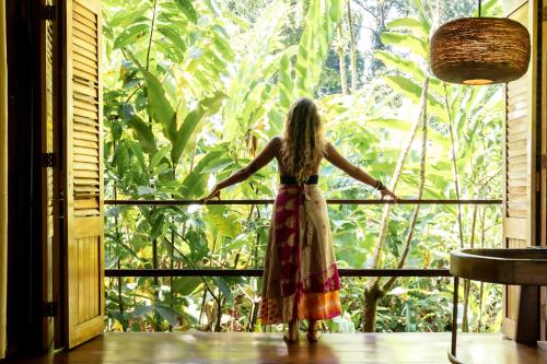 a woman looking out of a window at a forest at La Loma Jungle Lodge and Chocolate Farm in Bocas del Toro