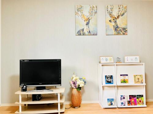 a tv sitting on a stand in a living room at Hana Home - New Cozy House with 4 bedrooms - 10min from Umeda in Osaka