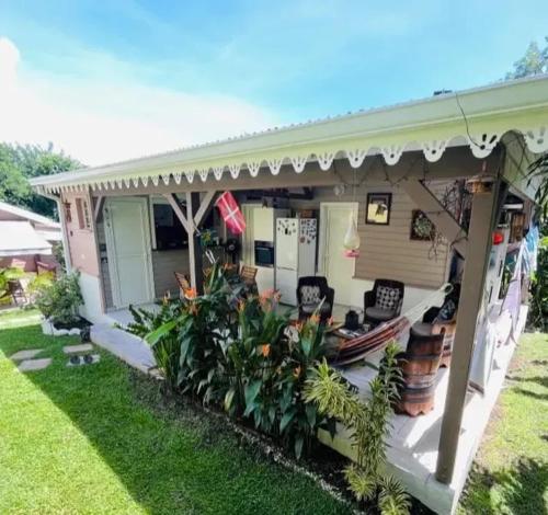 a house with a porch with chairs and plants at Maison confortable Le Diamant 40 m² avec piscine in Le Diamant