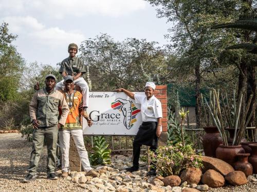 Un gruppo di uomini davanti a un cartello di Grace of Africa, Couples 5 STAR Nature Lodge a Marloth Park