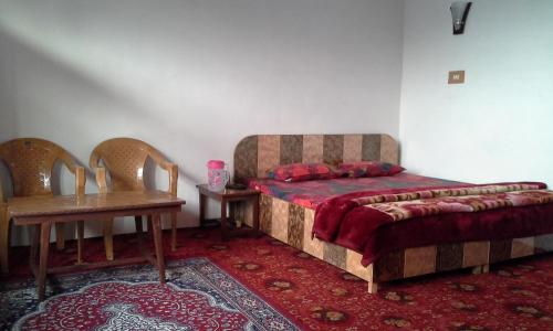 a bedroom with a bed and two chairs and a table at Howrah Guest House in Srinagar