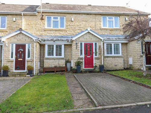 a brick house with red doors and a yard at Milo's Lodge in Glossop