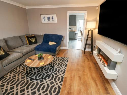 a living room with a couch and a tv at Milo's Lodge in Glossop