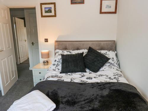 a bed with black and white sheets and pillows at Milo's Lodge in Glossop