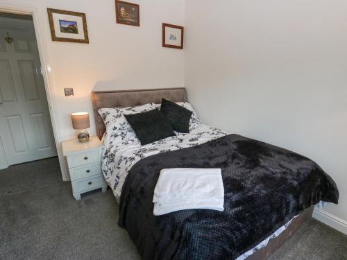 a bedroom with a bed with a black and white blanket at Milo's Lodge in Glossop