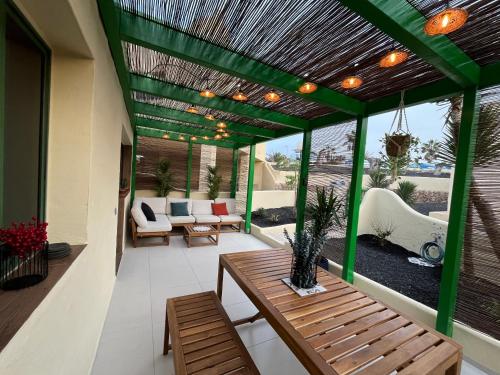 a patio with a green pergola and a wooden table at La Chata in Costa Calma