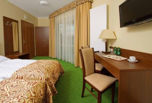 a hotel room with a bed and a desk with a computer at Hotel Zielony in Poznań
