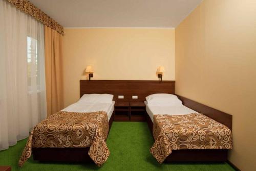 two beds in a hotel room with green carpet at Hotel Zielony in Poznań