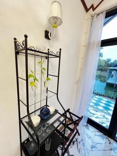 a black shelf with plants in a room with a window at Cozy breezing countryside Pet in Ban Khlong Sip Sam Lang