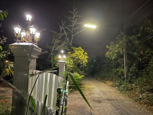 a street at night with a fence and lights at Cozy breezing countryside Pet in Ban Khlong Sip Sam Lang