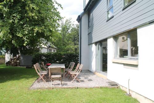 a patio with a table and chairs next to a house at Bright, contemporary house & large private garden in Strathpeffer