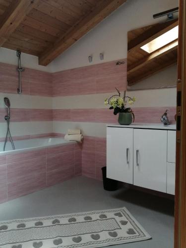 a bathroom with a tub and pink tiles at Villetta Muncion in Pozza di Fassa