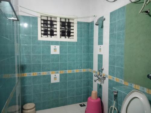 a bathroom with a toilet and a green tiled wall at Prashanth Family Homestay in Madikeri