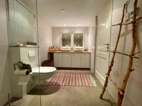 a bathroom with a toilet and two sinks at Your Private Zeeland Getaway - Cosy Home With Large Garden in Heinkensand