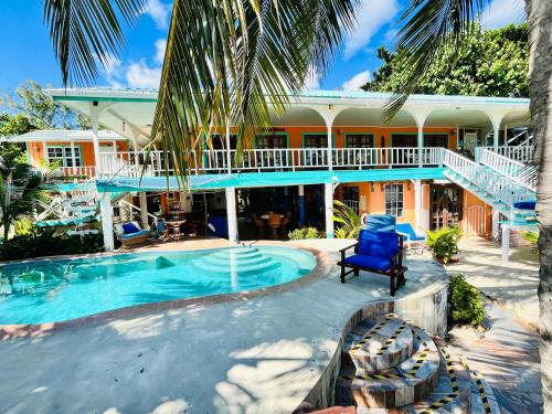 a resort with a swimming pool and a house at Coral Cove Inn in Maya Beach