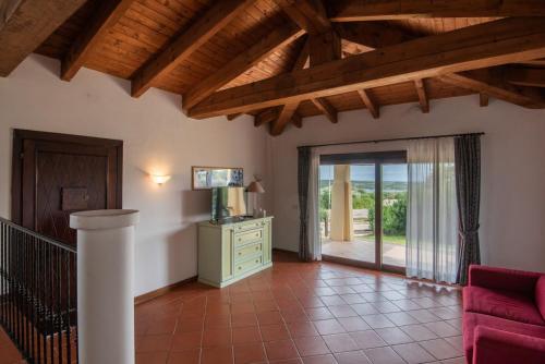 a living room with a red couch and a sliding glass door at Villetta Mare Blu With Pool, Country Village, Stintino in Cuile Pazzoni