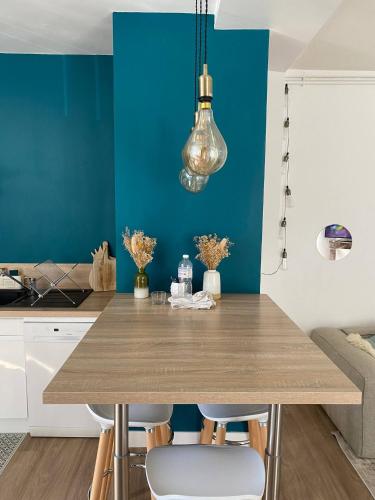 une cuisine avec une table en bois et un mur bleu dans l'établissement La Maison de Léa, à Périgueux