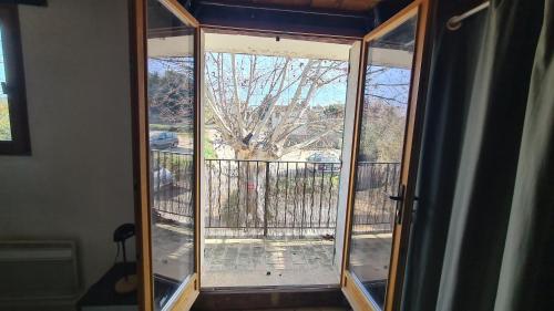 d'une porte coulissante en verre offrant une vue sur un arbre. dans l'établissement Joli studio meublé, à Cabriès