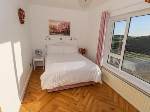 a bedroom with a bed and a large window at Castle Demesne House in Clifden