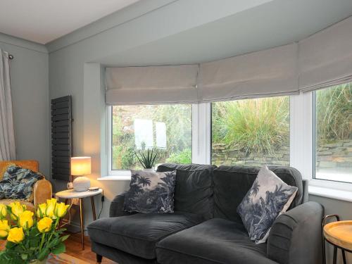a living room with a couch and two windows at Waves Edge in Torpoint