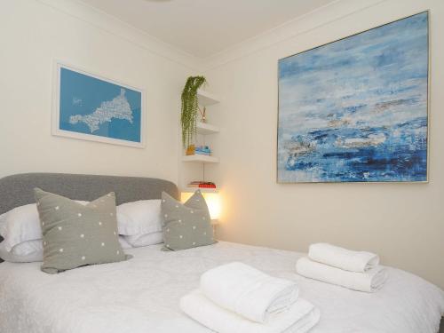 a bedroom with a bed with pillows and a painting at Waves Edge in Torpoint