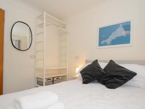 a bedroom with a white bed with black pillows at Waves Edge in Torpoint
