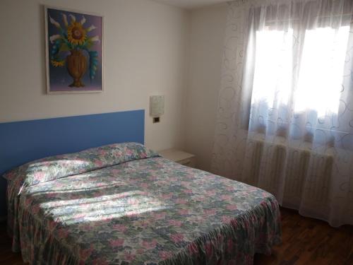 Schlafzimmer mit einem Bett und einem Fenster in der Unterkunft Apartment Maria & Patrizio in Lignano Sabbiadoro