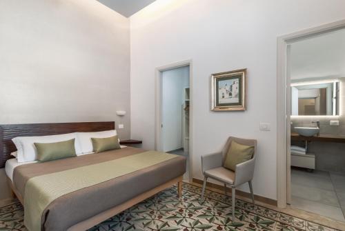 a bedroom with a bed and a chair in it at Palazzo San Lazzaro - Jacuzzi Rooms & Suites Lecce Selection in Lecce