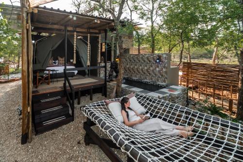 玛洛斯帕克Grace of Africa, Couples 5 STAR Nature Lodge的一名女子躺在凉亭的吊床上