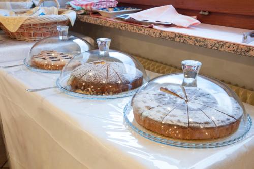 drie taarten in glazen koepels op een tafel bij Garnì Mariolina in Falcade