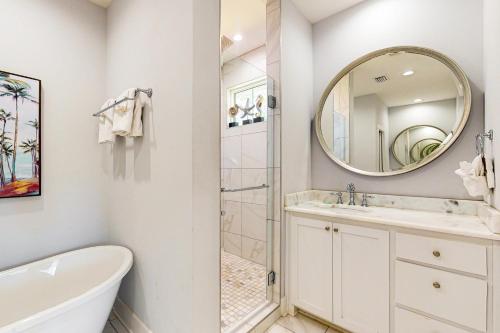 Un baño con bañera, lavabo y espejo. en Blue Luxe, en Pensacola