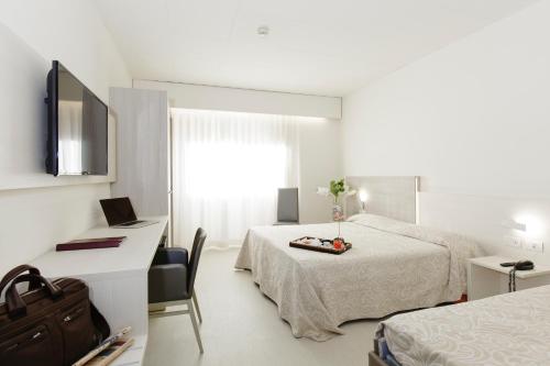 Habitación de hotel con cama, escritorio y TV. en Alfa Fiera Hotel, en Vicenza