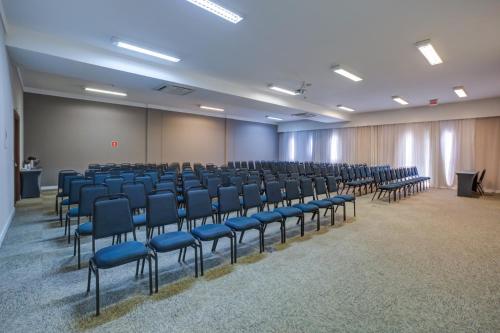 an empty room with blue chairs and a podium at Quality Hotel Jundiaí in Jundiaí