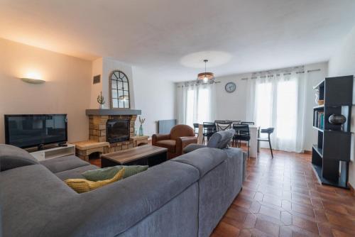 - un salon avec un canapé gris et une cheminée dans l'établissement Maison familiale à 10 min du Futuroscope, à Saint-Georges-lès-Baillargeaux