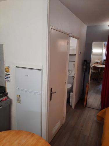 Cette chambre dispose d'un réfrigérateur blanc et d'une porte. dans l'établissement Duplex14h 1er étage jardinet 1 parking ou studio14B rdc terrasse sans parking, à La Rochelle