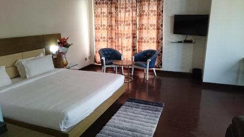 a bedroom with a bed and a table and chairs at Rosewood International Hotel in Bengaluru