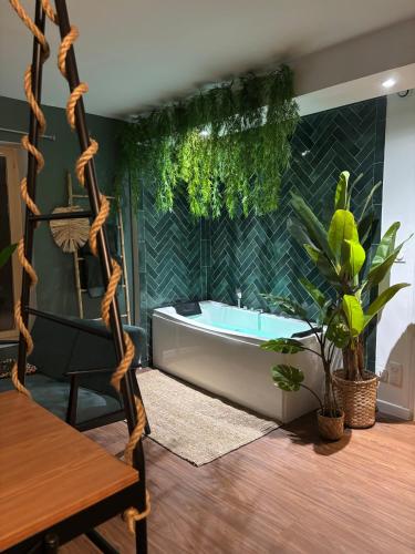 La salle de bains est pourvue d'une baignoire et d'une plante. dans l'établissement Jungle Fever , évasion nature et balnéo, à Boulogne-sur-Mer