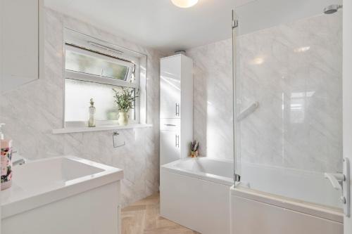 a white bathroom with a tub and a sink at Gorse Cottage - Sea Views Village Centre in Penally