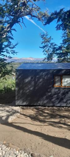 un edificio nero in cima a una strada sterrata di dormis bar a San Martín de los Andes