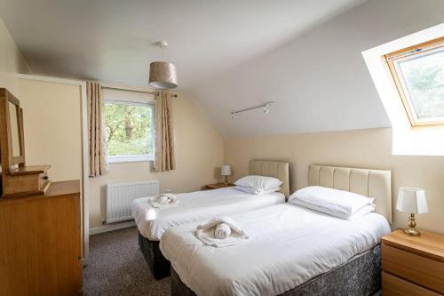 a bedroom with two beds with towels on them at Norbury, woodland lodge with hot tub for 12 in Oakamoor
