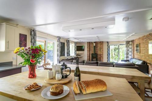 a kitchen and living room with a table with bread at Norbury, woodland lodge with hot tub for 12 in Oakamoor