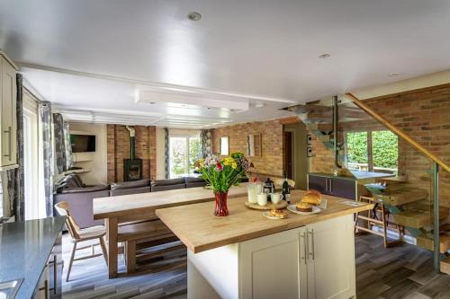 a kitchen with a table and a dining room at Norbury, woodland lodge with hot tub for 12 in Oakamoor