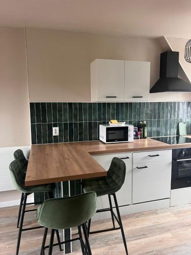 une cuisine avec une table en bois et des chaises vertes dans l'établissement NEW, Strasbourg T2 Neuf Proche Parlement, à Strasbourg