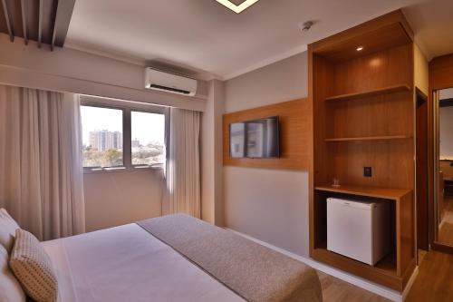 a bedroom with a bed and a tv and a window at Quality Hotel Jundiaí in Jundiaí